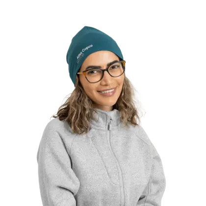 woman wearing teal beanie with atlas copco group logo